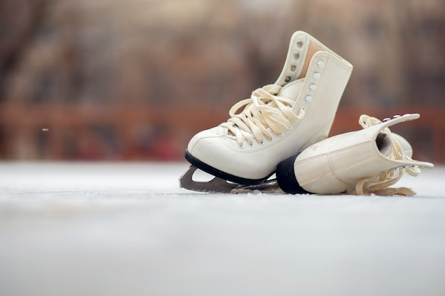 Un par de patines blancos se encuentran en una pista de hielo abierta