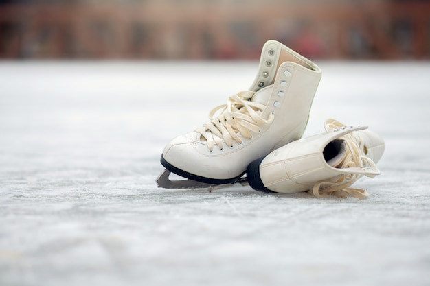 Un par de patines blancos se encuentran en una pista de hielo abierta