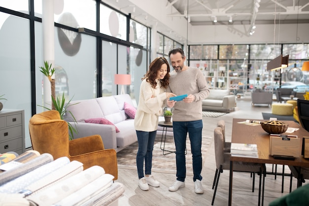 Par de pie en el salón de muebles viendo algo en internet