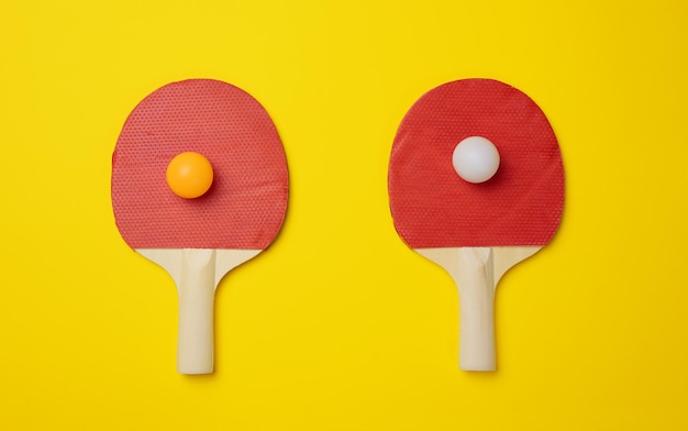 Par de raquetas de tenis de madera para ping pong sobre un fondo amarillo