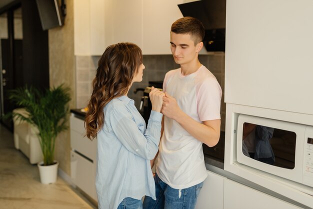 Par romântico em casa. Mulher jovem e atraente e homem bonito estão aproveitando a passar tempo juntos em pé na cozinha moderna. Conceito de relacionamento.