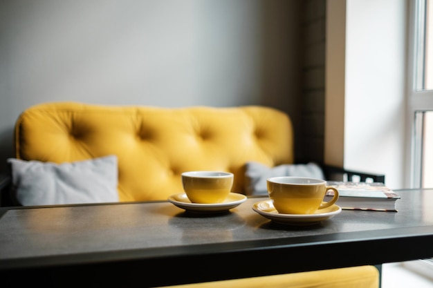 Foto un par de tazas de café en una cafetería vacía platos amarillos y un sofá en un restaurante sin invitados