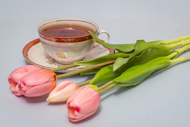 Par de té de porcelana vintage con té y un ramo de tulipanes.