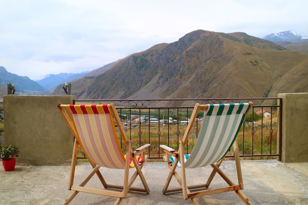 Par de tumbonas vacías en la terraza contra la hermosa vista a la montaña