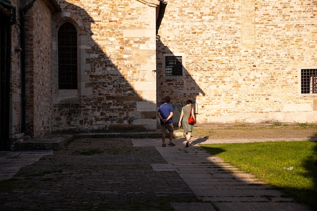 Par de turistas caminando junto a la Basilica di Santa Maria Assunta Aquileia