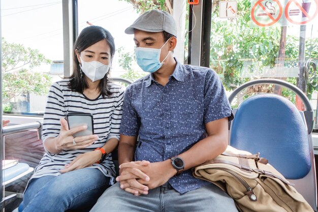 Par viajar en autobús público juntos vistiendo mascarilla