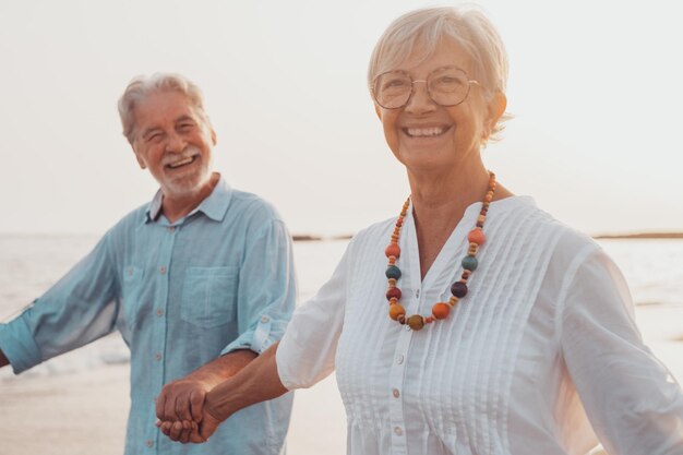 Un par de viejos maduros caminando juntos sobre la arena y divirtiéndose en la arena de la playa disfrutando y viviendo el momento Dos lindos ancianos enamorados divirtiéndose Descalzos caminando sobre el aguaxA