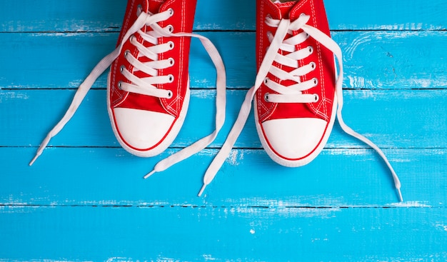 Par de zapatillas rojas con cordones blancos.