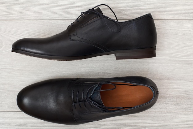 Par de zapatos de hombre de cuero negro sobre fondo de madera gris Zapatos elegantes y con estilo para hombres