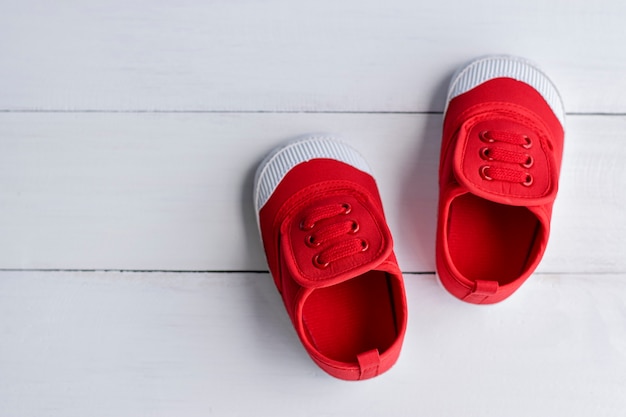 Foto un par de zapatos rojos del bebé en el suelo de madera blanco
