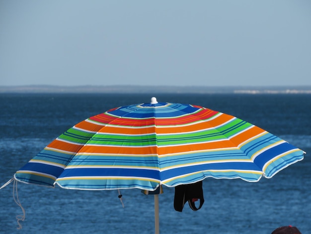 Foto para-chuvas multicoloridas na praia contra o céu claro