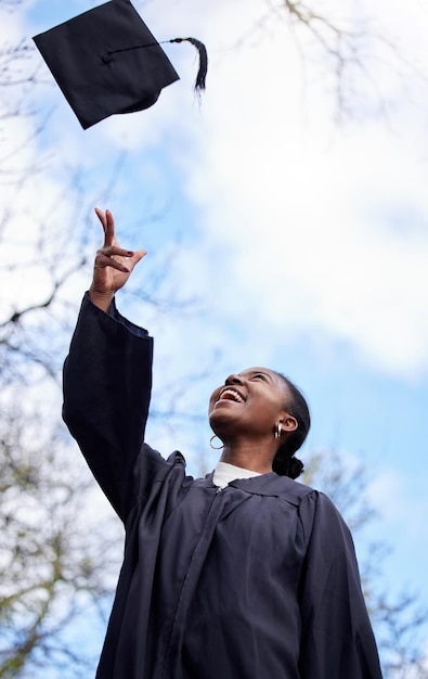 Para cima e para a frente a partir daqui. Foto de uma jovem jogando o chapéu no ar no dia da formatura.