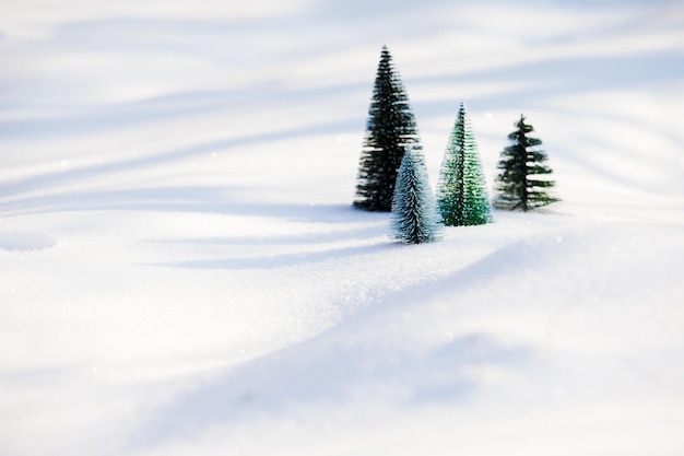 Para pequenas árvores de natal artificiais que ficam ao lado umas das outras na neve fresca e macia. Vista de manhã ensolarada e gelada de pequenos abetos na neve, salvando o conceito de natureza