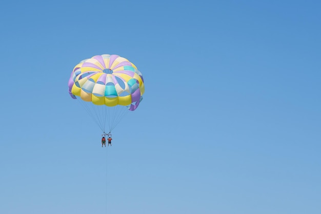 Pára-quedas de parapente colorido contra um céu azul claro