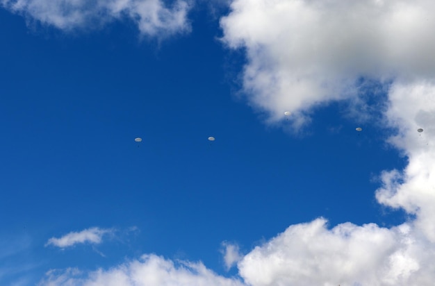 pára-quedistas exercícios militares paraquedismo de um helicóptero contra o fundo de nuvens e céu azul no verão foto horizontal vista inferior