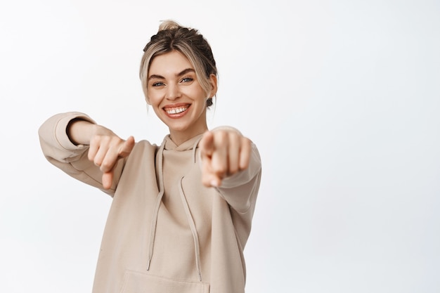 Parabéns. mulher bonita sorridente apontando os dedos, escolhendo você, de pé em branco. copie o espaço