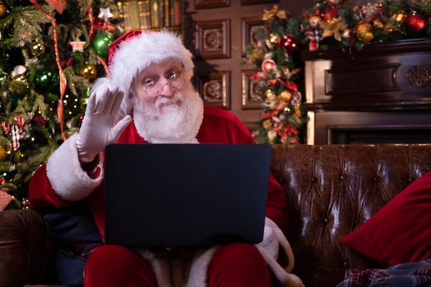 Parabéns online de Natal do Papai Noel. Papai Noel usando notebook laptop à distância