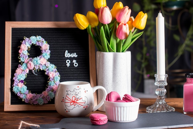 Parabéns pelo Dia Internacional da Mulher em 8 de março Cartão de saudação com uma chávena de bebida quente com flores e doces rosados