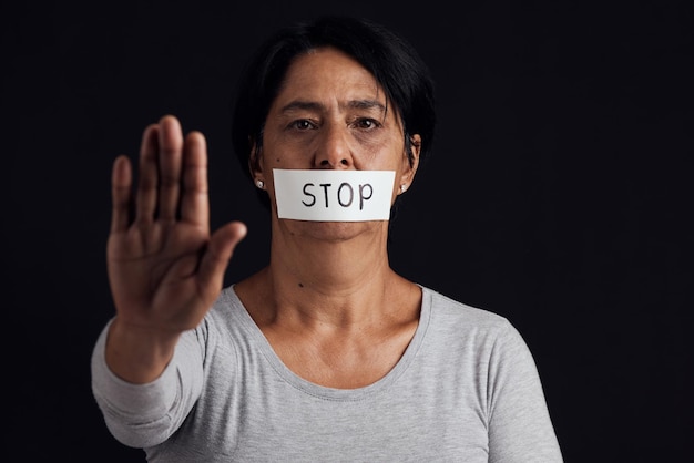 Parada de retrato y palma con una mujer en el estudio sobre un fondo negro para la igualdad de género o la violencia doméstica Silencio de manos o abuso y una víctima asustada con la boca cubierta de miedo