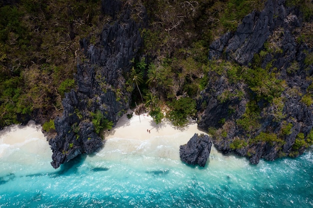 Foto paradiesischer strand mit türkisfarbenem wasser und ein paar, das sich alleine auf einer insel auf den philippinen vergnügt