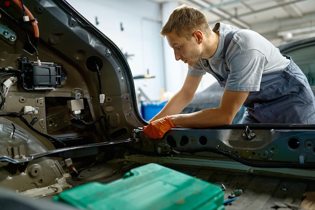 Parafuso de fixação do trabalhador durante o reparo do corpo do carro