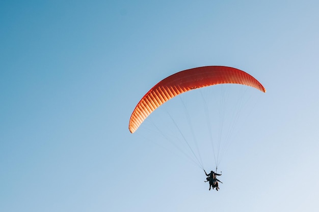 Paraglider fliegt über den blauen Himmel Konzept des Extremsports, das Abenteuer herausfordert.