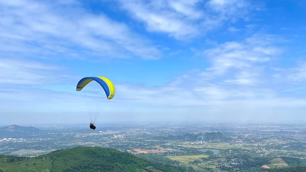 Paragliders voando sobre a bela paisagem de montanha, sob um céu azul com nuvens.