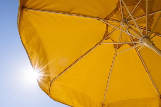 Paraguas amarillo y rayos de sol.