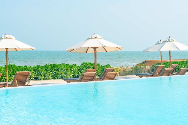 Paraguas con cama piscina alrededor de la piscina con fondo de mar océano