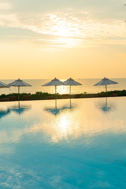 Paraguas con cama piscina alrededor de la piscina con fondo de mar océano