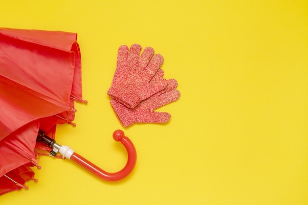 Foto paraguas y guantes rojos para niños sobre un fondo amarillo con espacio para copiar