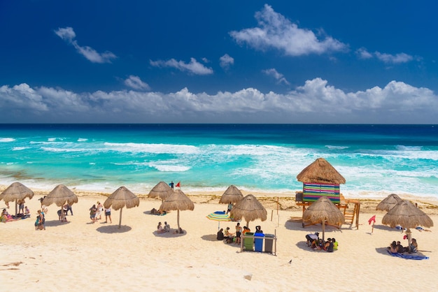 Paraguas en una playa de arena con agua azul en un día soleado cerca de Cancún México