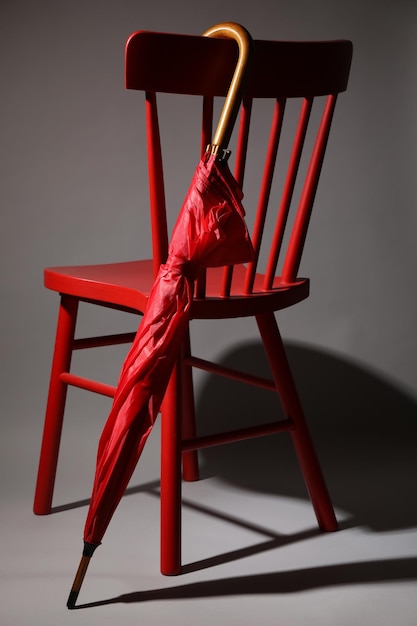 Foto paraguas rojo elegante y silla sobre fondo gris