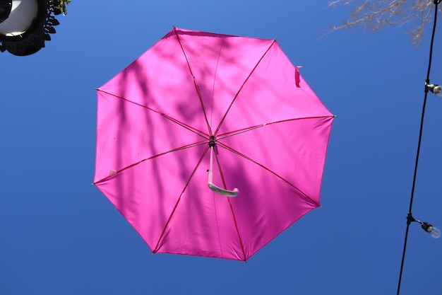 Un paraguas rosa está volando en el cielo.