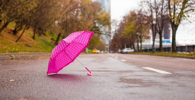 Paraguas rosa para niños sobre el asfalto mojado al aire libre
