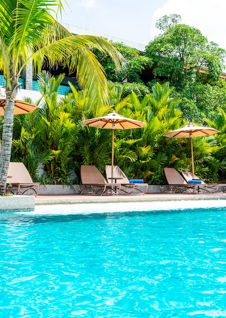 Paraguas y silla alrededor de la piscina en el hotel y resort