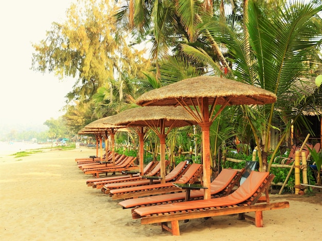 Foto paraguas sobre sillas de descanso en la orilla