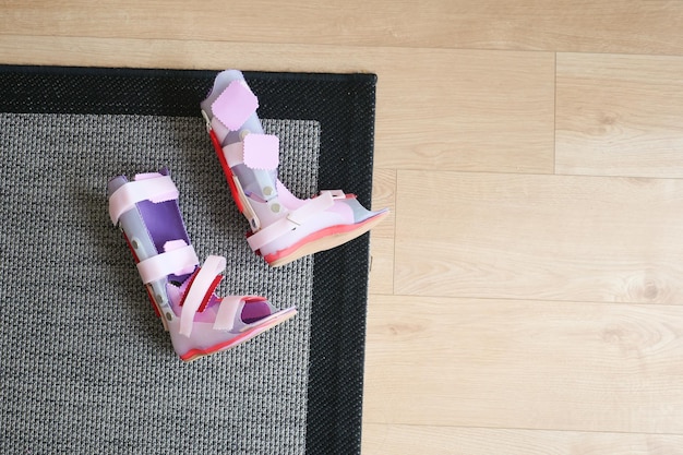 Parálisis cerebral infantil discapacidad piernas ortesis zapatos en el suelo en casa