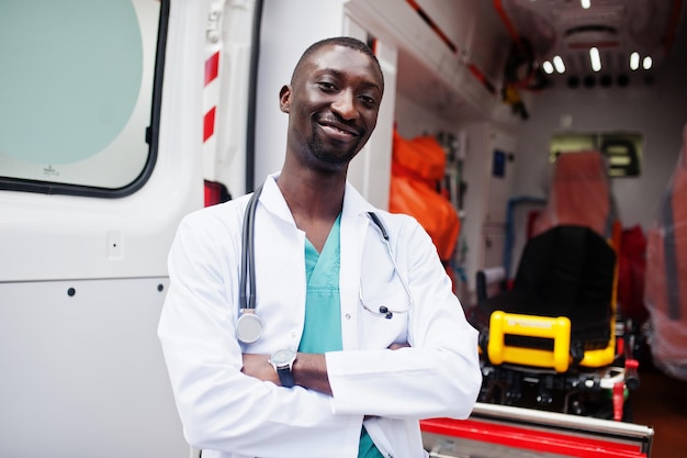 Paramédico africano parado frente a un camión de ambulancia.