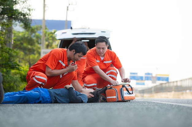 El paramédico está asistiendo a un hombre herido en una situación de emergencia en la carretera