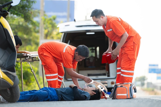 El paramédico está asistiendo a un hombre herido en una situación de emergencia en la carretera