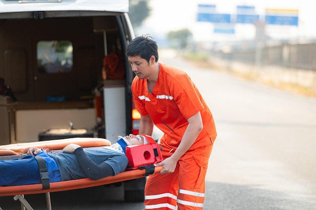 El paramédico está asistiendo a un hombre herido en una situación de emergencia en la carretera