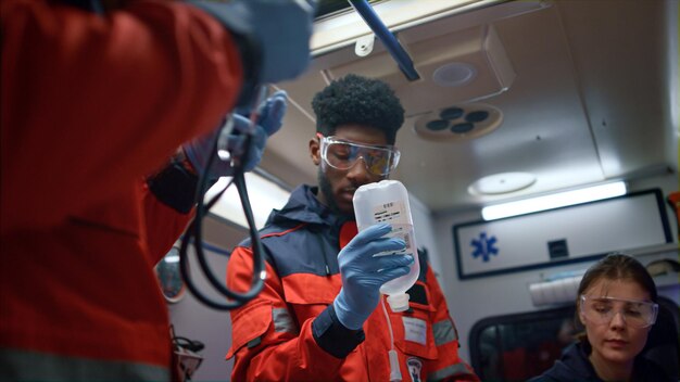 Foto paramedicos multiétnicos que prestan atención de emergencia al paciente en un vehículo de emergencia equipo de ambulancia que utiliza estetoscopio en el trabajo médicos de emergencia que proporcionan ayuda de ambulancias en el turno nocturno concepto de medicina