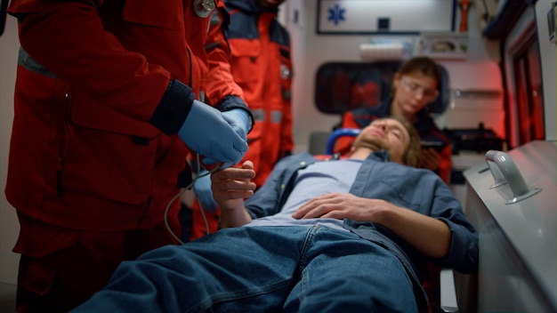 Foto paramedicos profissionais verificando o nível de oxigênio no sangue da vítima médicos de ambulância prestando ajuda médica a um homem em veículo de emergência pessoal médico de raça mista resgatando paciente conceito médico