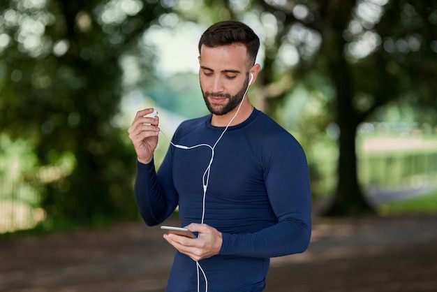 Parando para verificar suas mensagens Foto recortada de um jovem e bonito corredor verificando suas mensagens durante o treino