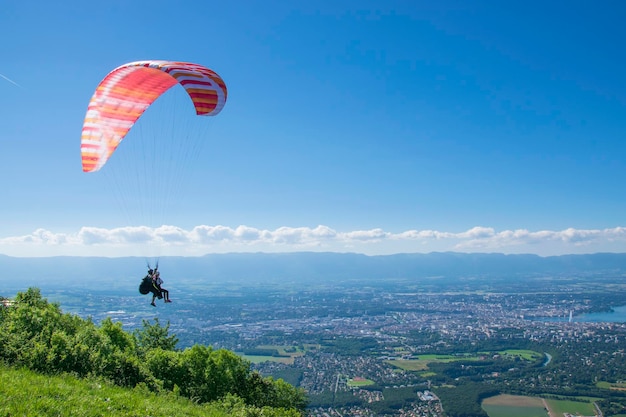 Parapente com um pára-quedas vermelho está observando Genebra do ar.