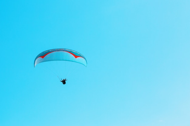 Parapente se eleva contra el cielo azul con espacio despejado