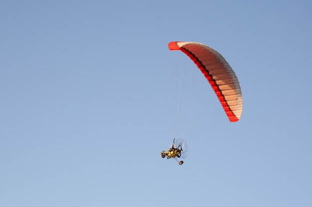 Parapente motorizado sobrevoando montanhas em dia de verão