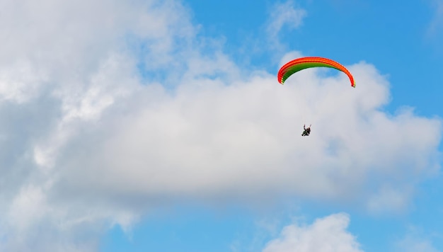 Parapente naranja y verde bajo las nubes