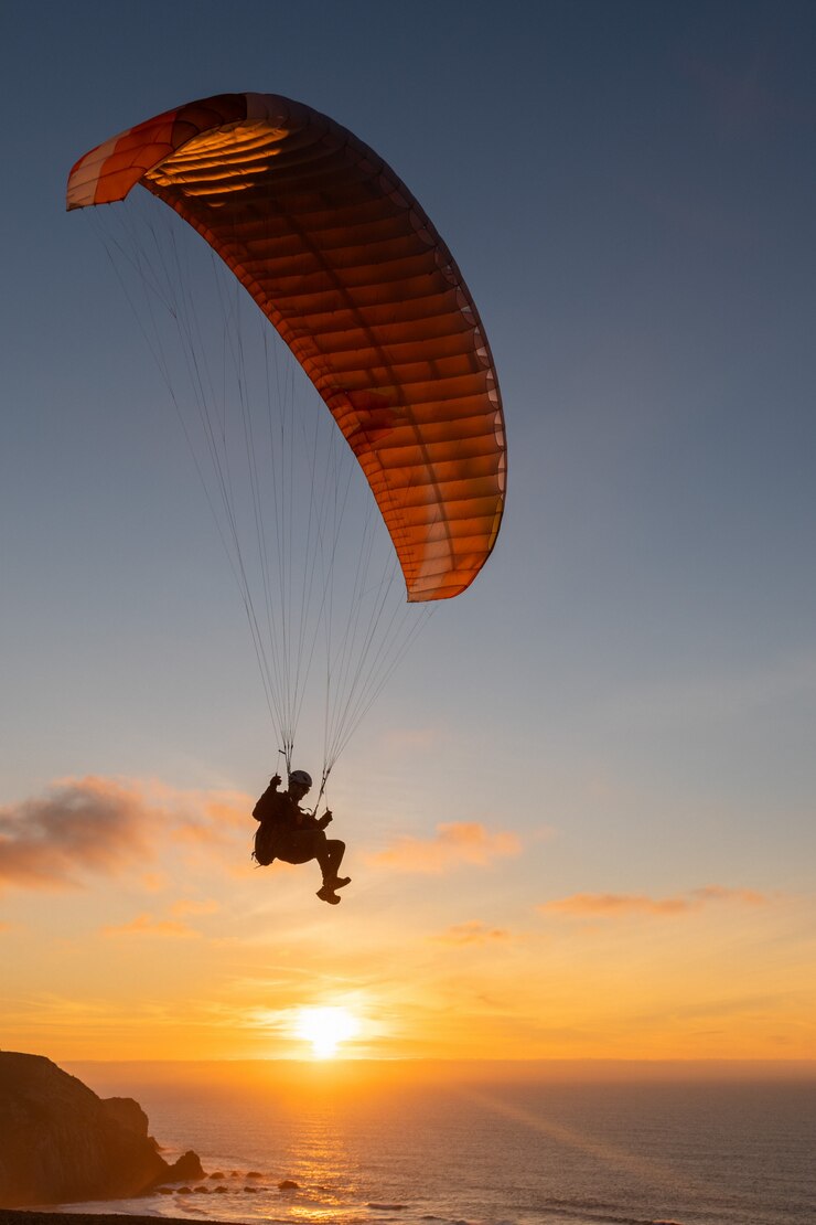 Parapente que voa sobre a costa do mar no por do sol. Esporte de parapente